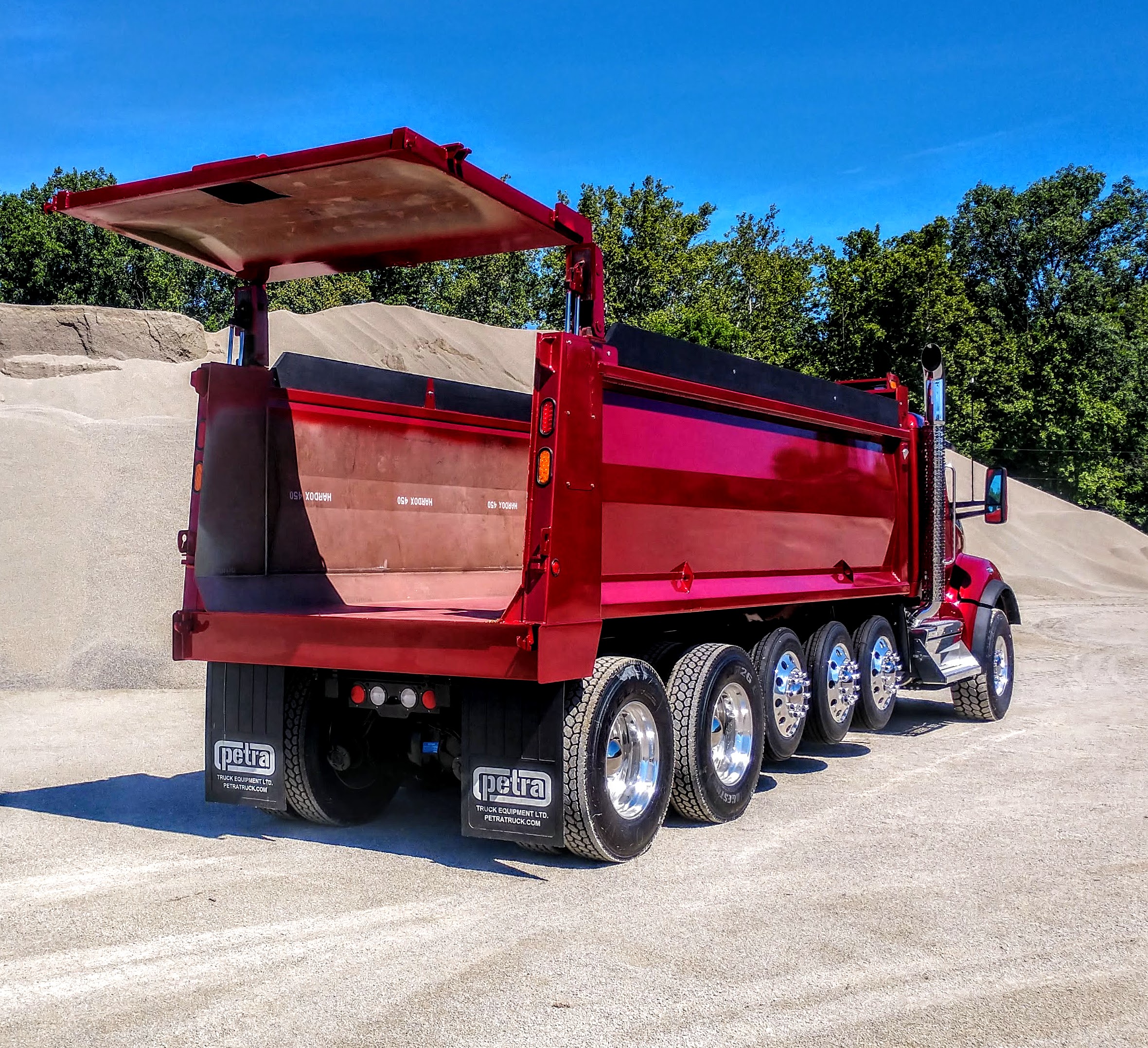 Red commercial truck with Hardox steel flat floor dump body installed by Petra Truck Equipment showing smooth level design